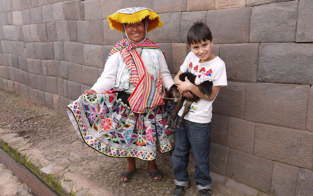 pisac lady and child with lamb cusco peru